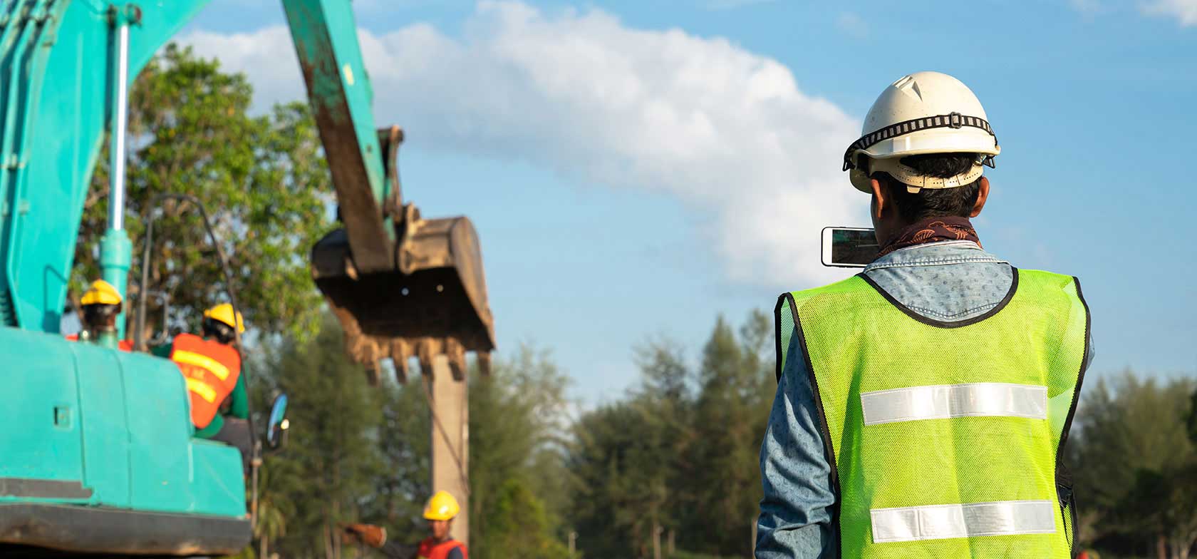 A LSSE field team completes work in the field wearing safety vests while an engineer takes a photo using their iPhone
